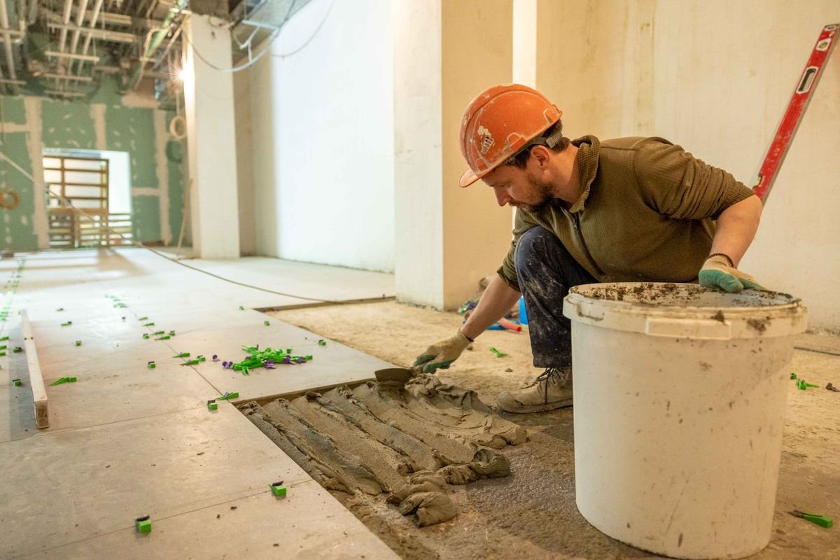 Worker installing floor tiles during an interior renovation