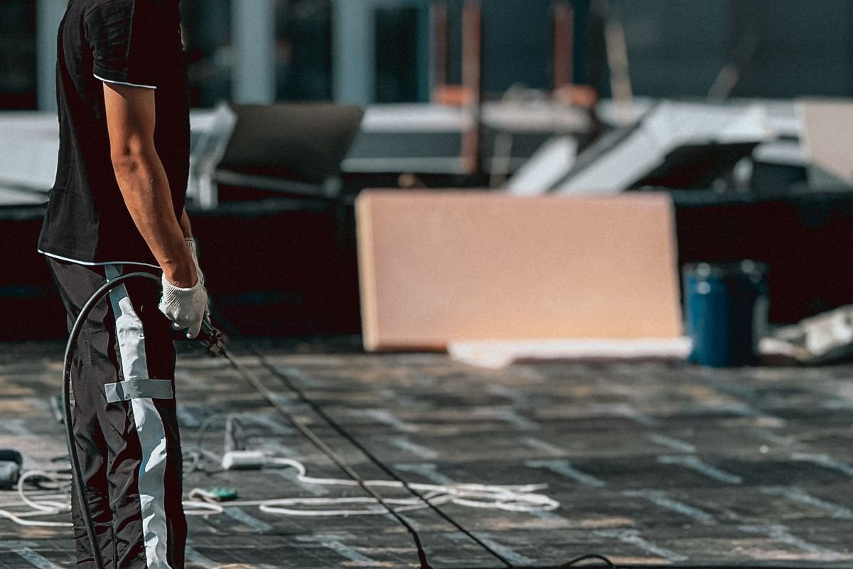 Worker applying a waterproofing coating to a roof